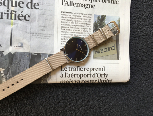 Montre parisienne avec un journal écrit en français derrière.